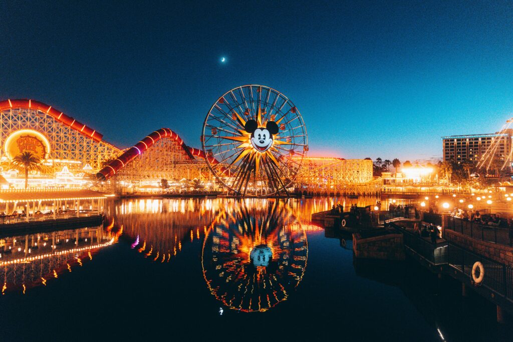 Stunning night view of Disneyland's Pixar Pier with Mickey Mouse Ferris wheel and reflected lights.